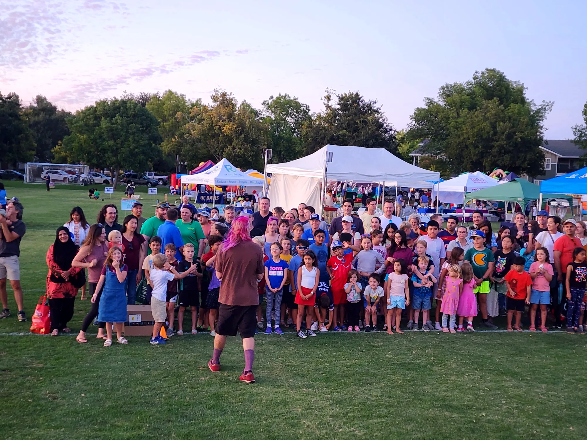 Diverse Davis families gathered at dusk on the Community Park lawn during Family Fun Fest