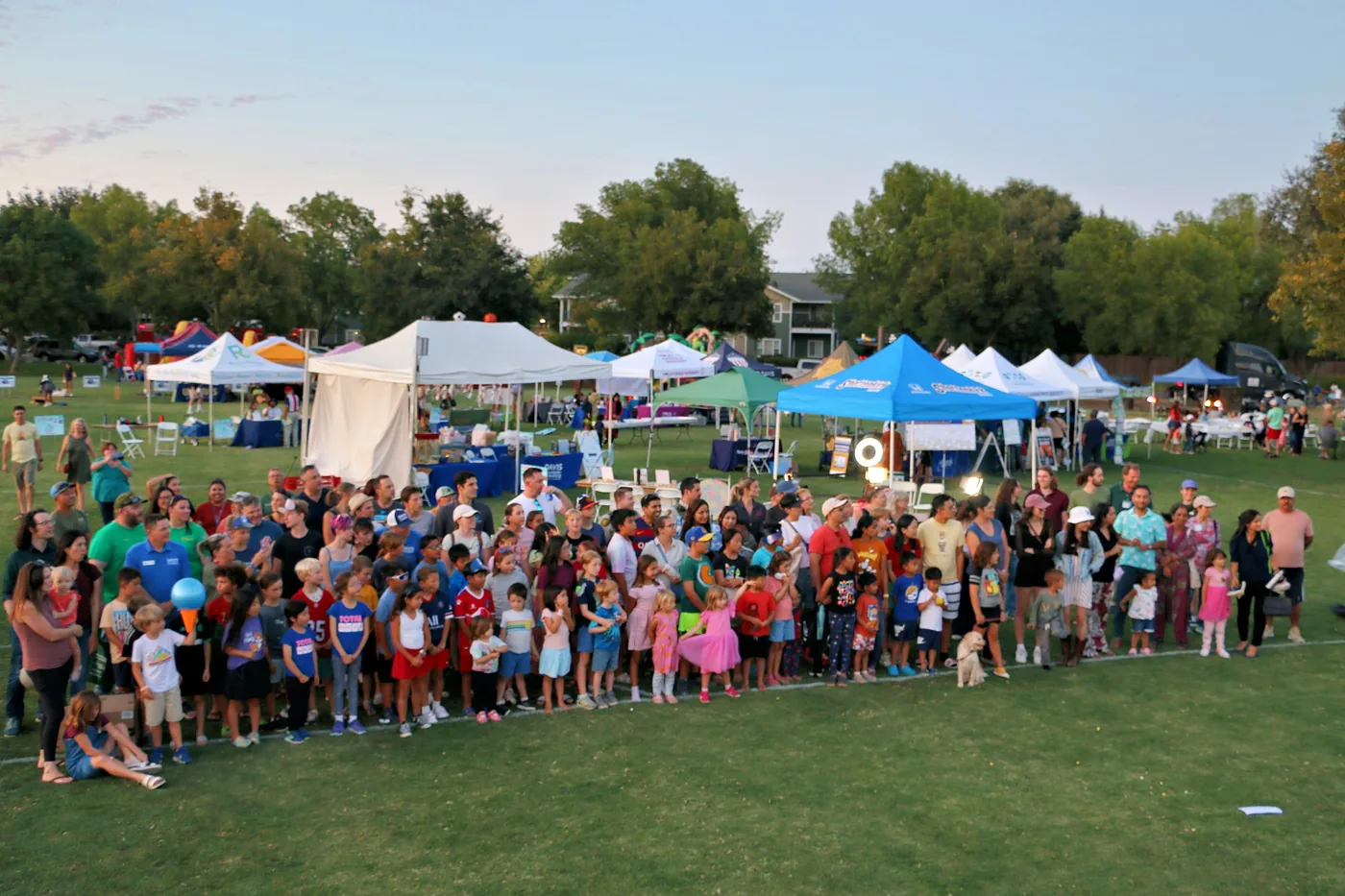 A golden-hour group photo of Davis Chamber members and families gathered together at Family Fun Fest