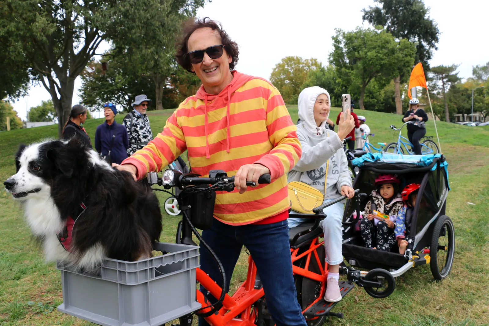 A smiling participant in a bright vest poses with a dog at the bike event